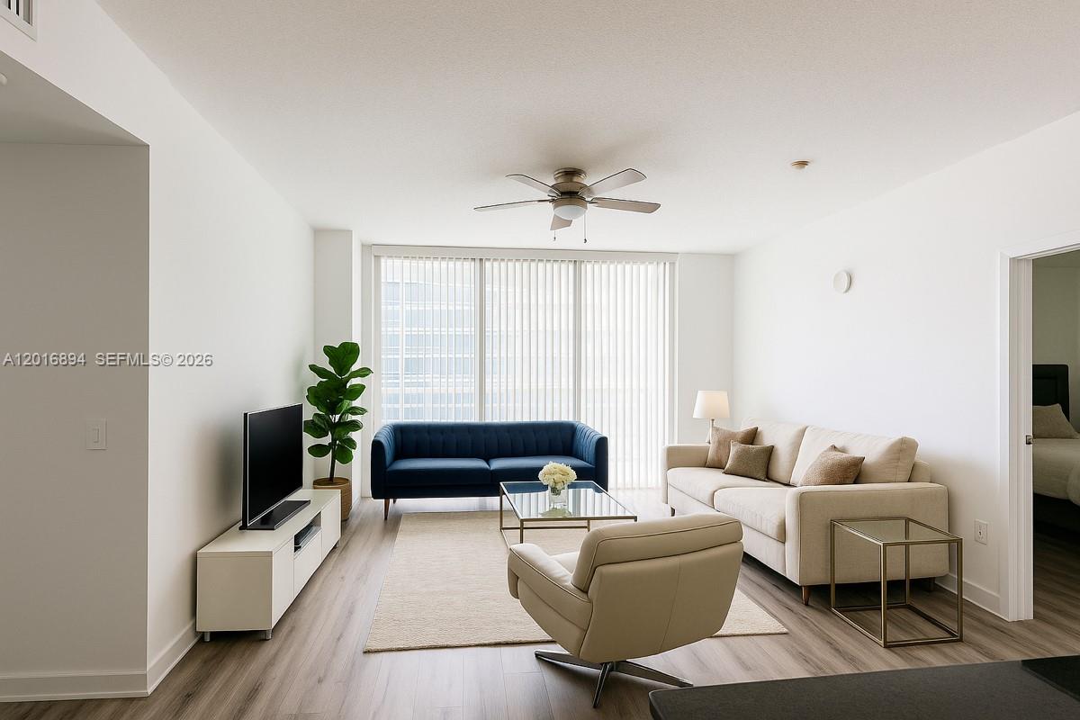 A living room features a blue sofa, a beige sofa, and a swivel armchair — 79 SW 12th St, Miami FL 33130, MIAMI, FL