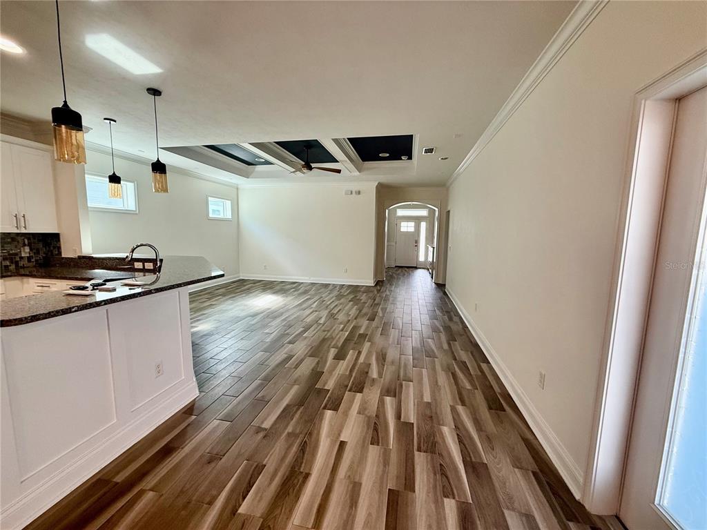 A kitchen island overlooks a living area with wood-look tile floors and a tray ceiling — 3635 NW 26TH STREET, GAINESVILLE, FL