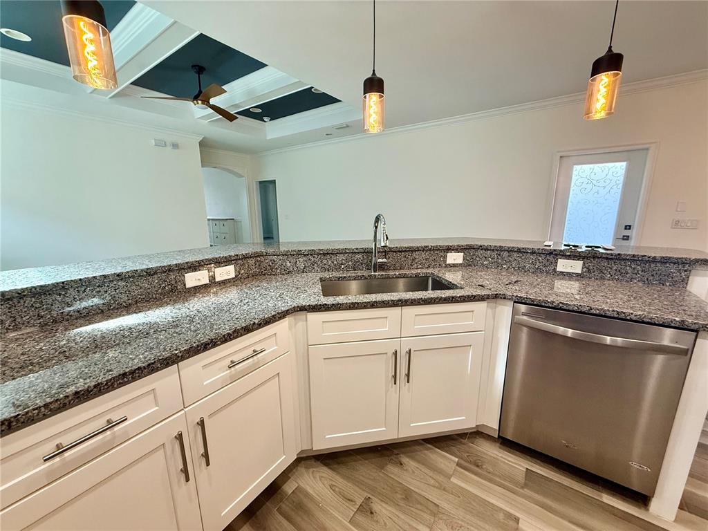 A kitchen features white cabinets, granite countertops, a stainless steel sink, and pendant lighting — 3635 NW 26TH STREET, GAINESVILLE, FL