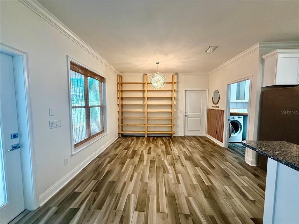 A dining area features wood-look flooring, a large wooden shelving unit, and a modern light fixture — 3635 NW 26TH STREET, GAINESVILLE, FL