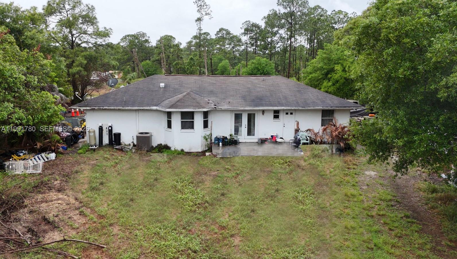 The rear exterior of a single-story white house features a patio and a grassy yard — 825 N Willow ST, Clewiston FL 33440, CLEWISTON, FL