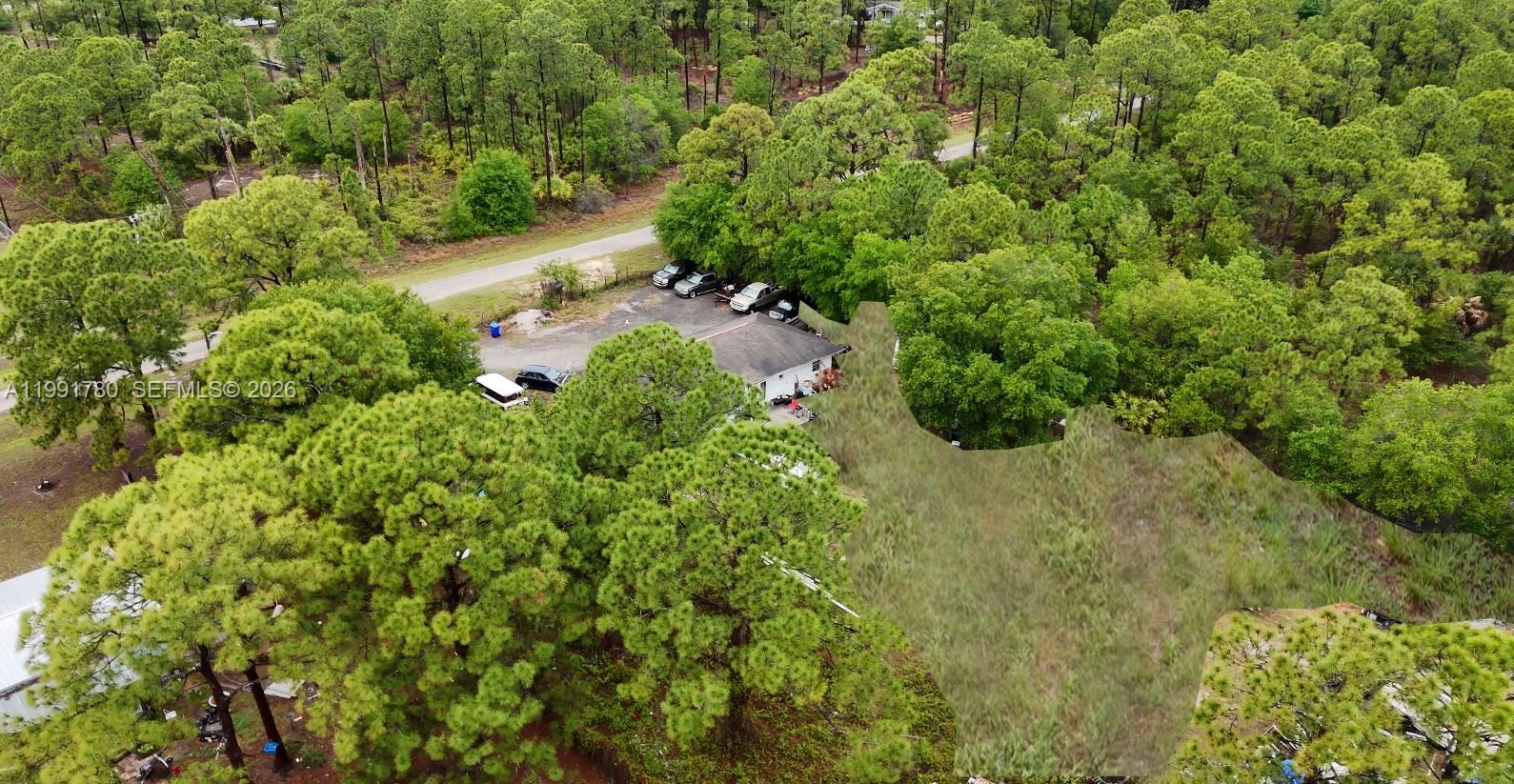 An aerial view shows a house surrounded by trees with a gravel parking area — 825 N Willow ST, Clewiston FL 33440, CLEWISTON, FL