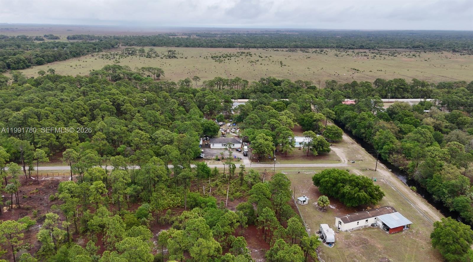 An aerial view shows a rural property with two houses surrounded by trees and fields — 825 N Willow ST, Clewiston FL 33440, CLEWISTON, FL