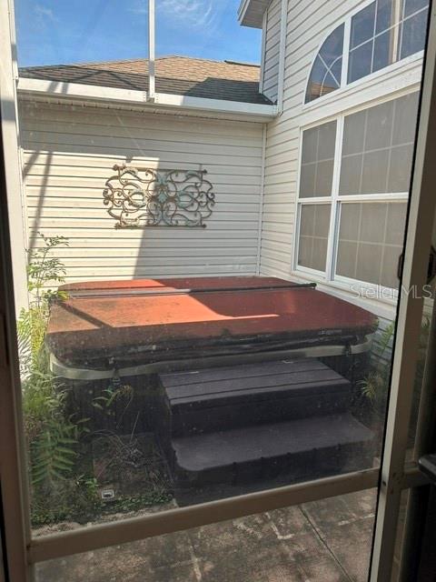 A hot tub with a cover and steps sits on a patio inside a screen enclosure — 992 RIDGELAND PATH, THE VILLAGES, FL