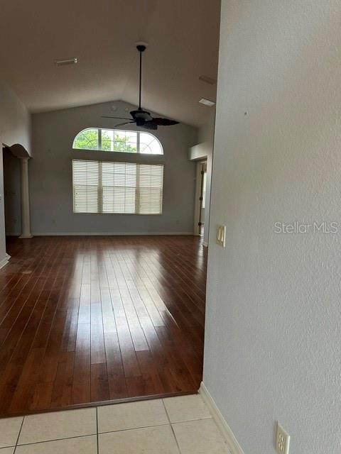 A living room features dark wood flooring, a vaulted ceiling with a fan, and large windows — 992 RIDGELAND PATH, THE VILLAGES, FL
