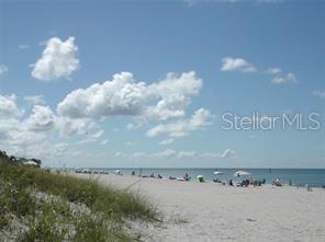 A wide, sandy beach with people and umbrellas under a blue sky with scattered clouds — 7177 BOUGAINVILLEA STREET, ENGLEWOOD, FL