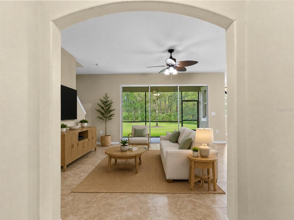 A living room with tile floors, a beige sofa, and sliding doors leading to a lanai — 20542 GRAND VISTA LANE, TAMPA, FL