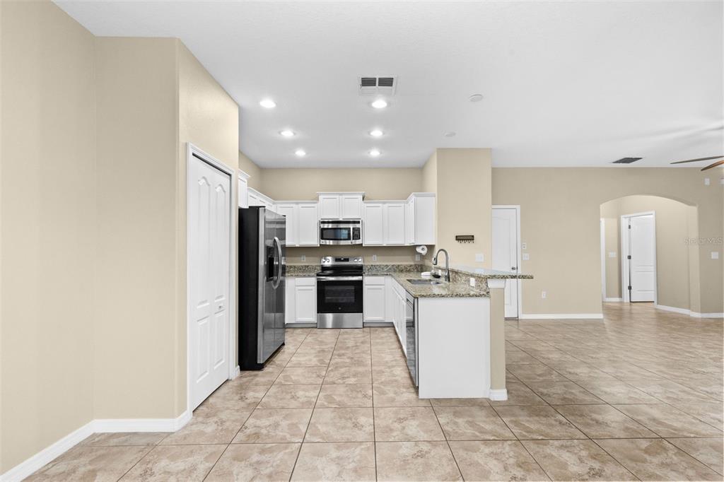 A kitchen with white cabinets, stainless steel appliances, granite countertops, and light-colored tile flooring — 20542 GRAND VISTA LANE, TAMPA, FL
