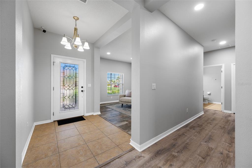 An entryway features tile flooring, a glass-paneled front door, and a transition to wood flooring — 1405 PARKER DEN DRIVE, RUSKIN, FL