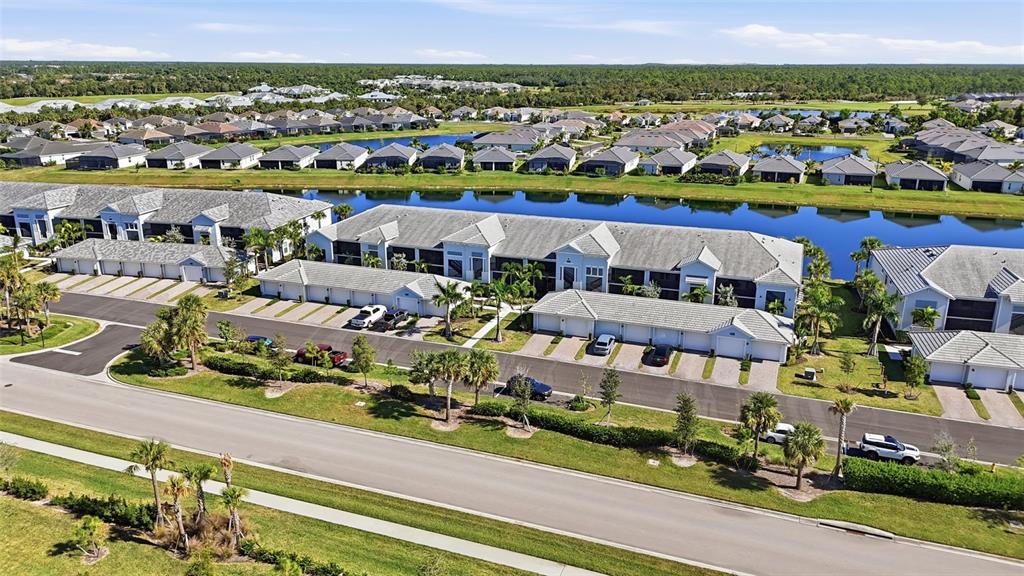 An aerial view shows multi-unit residential buildings with attached garages beside a long pond — 14204 HERITAGE LANDING BOULEVARD UNIT 712, PUNTA GORDA, FL