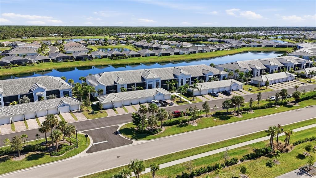 An aerial view shows a residential community with townhomes, a lake, and paved streets — 14204 HERITAGE LANDING BOULEVARD UNIT 712, PUNTA GORDA, FL