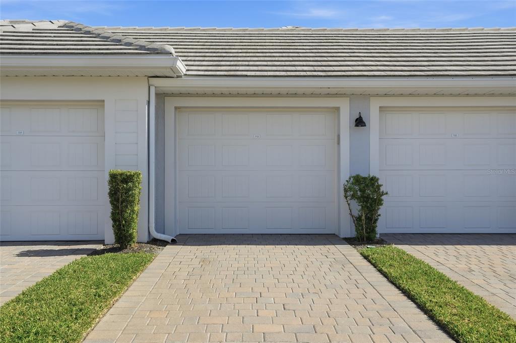 A row of three white garage doors with paved driveways and small shrubs in front — 14204 HERITAGE LANDING BOULEVARD UNIT 712, PUNTA GORDA, FL