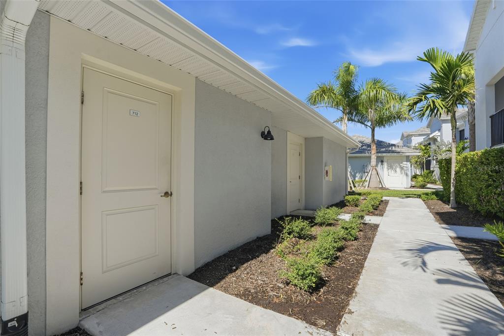 A view of a building exterior with a numbered door and a concrete walkway — 14204 HERITAGE LANDING BOULEVARD UNIT 712, PUNTA GORDA, FL