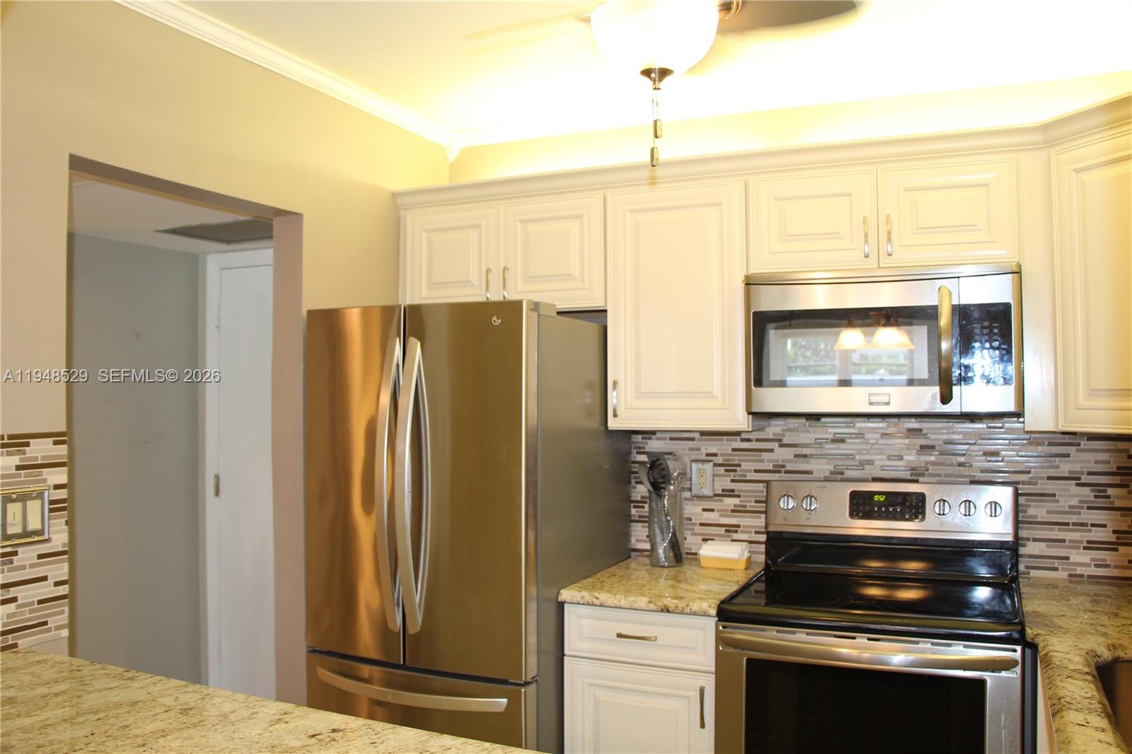 A kitchen features white cabinets, stainless steel appliances, and a granite countertop — 5620 SW 3rd Pl # 114, Margate FL 33068, MARGATE, FL