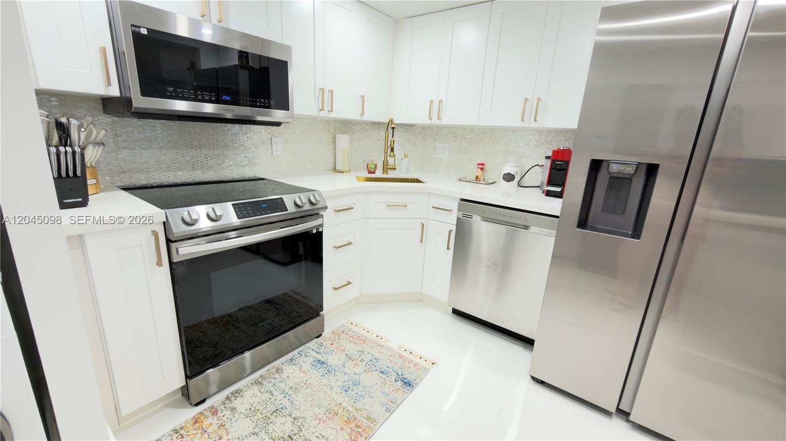 A modern kitchen features white cabinets, stainless steel appliances, and a gold-toned faucet — 2333 Brickell Ave # 614, Miami FL 33129, MIAMI, FL