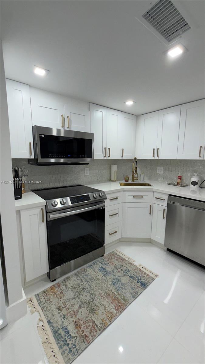 A modern kitchen features white cabinets, stainless steel appliances, and a patterned area rug — 2333 Brickell Ave # 614, Miami FL 33129, MIAMI, FL