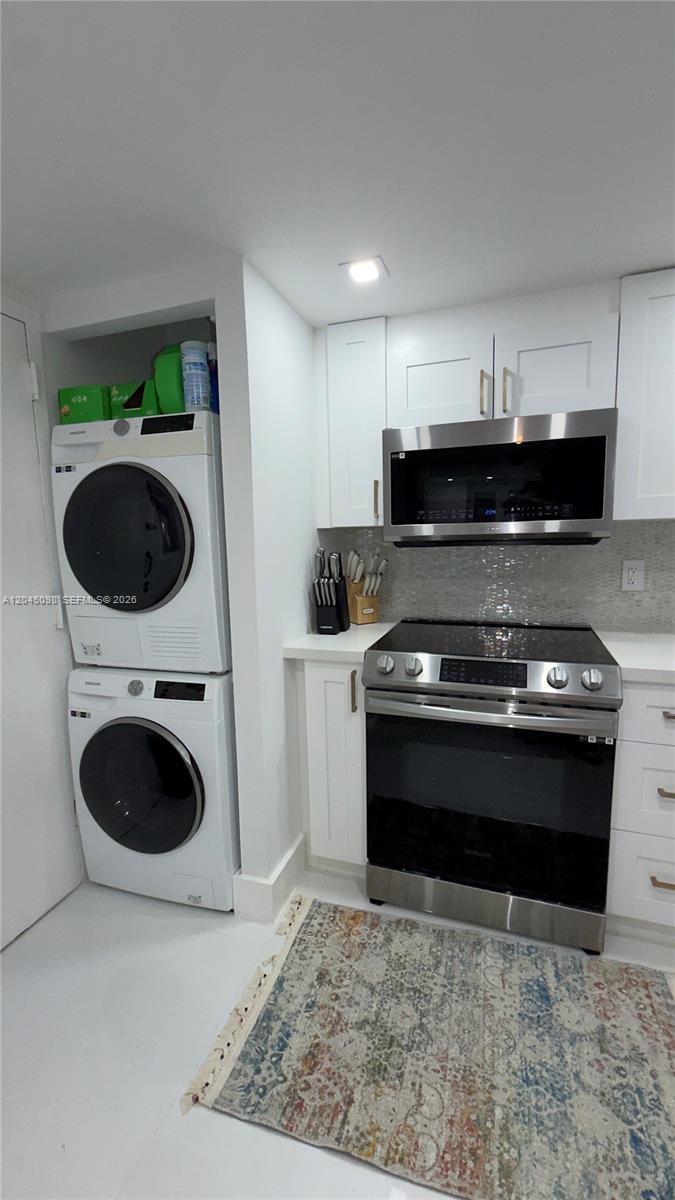 A kitchen features white cabinetry, stainless steel appliances, and a stacked washer and dryer unit — 2333 Brickell Ave # 614, Miami FL 33129, MIAMI, FL