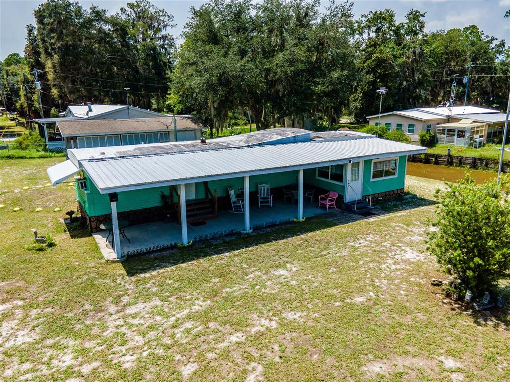 An elevated teal mobile home with a metal roof and a covered front porch — 23673 NE 134TH LANE ROAD, FORT MC COY, FL