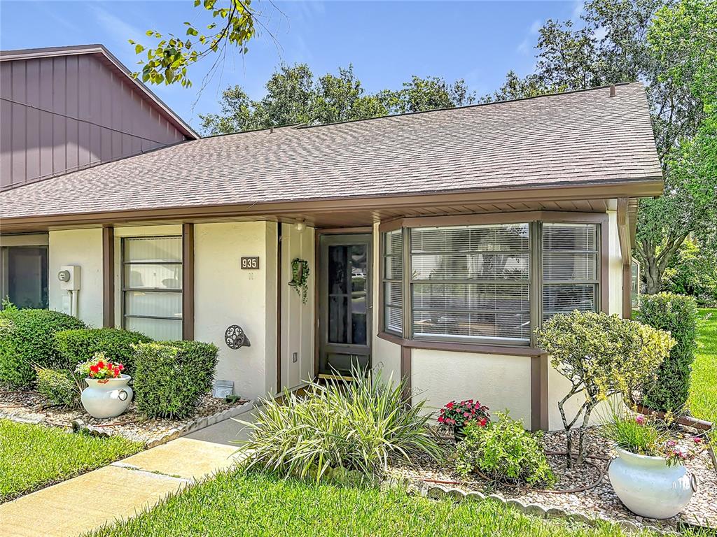 A single-story residential building exterior features a bay window, a front door, and landscaping — 935 EASTRIDGE DRIVE UNIT 7A, DEBARY, FL