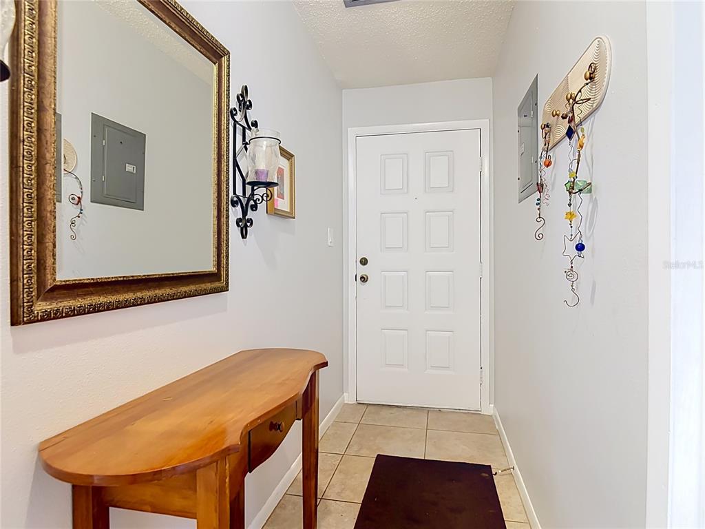 An entryway features a wooden console table, a large mirror, and a white front door — 935 EASTRIDGE DRIVE UNIT 7A, DEBARY, FL