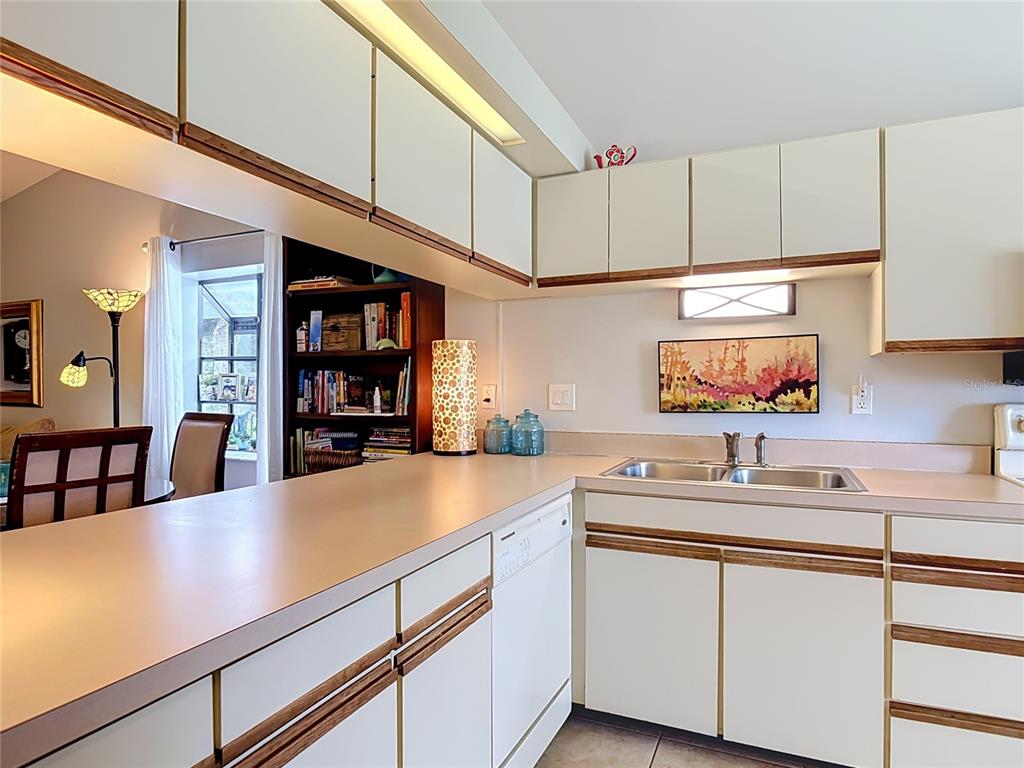 A kitchen features white cabinets with wood trim, a laminate countertop, and a double sink — 935 EASTRIDGE DRIVE UNIT 7A, DEBARY, FL