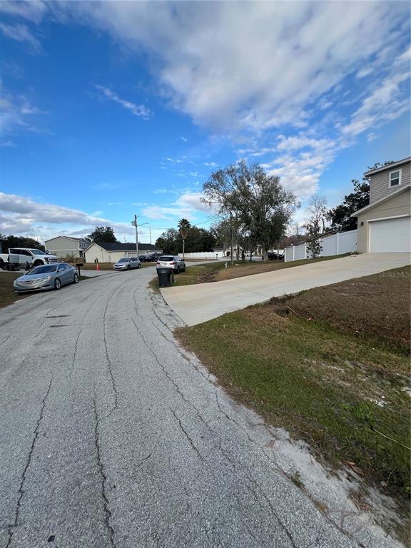 A paved driveway leads to a house exterior with a white garage door and fence — 1425 TEAL DRIVE, KISSIMMEE, FL