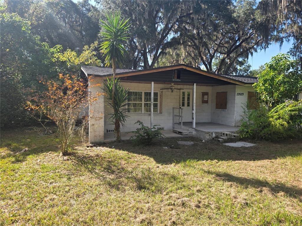 A single-story concrete block house with a covered front porch sits on a grassy lot — 22629 SE 71ST AVENUE, HAWTHORNE, FL