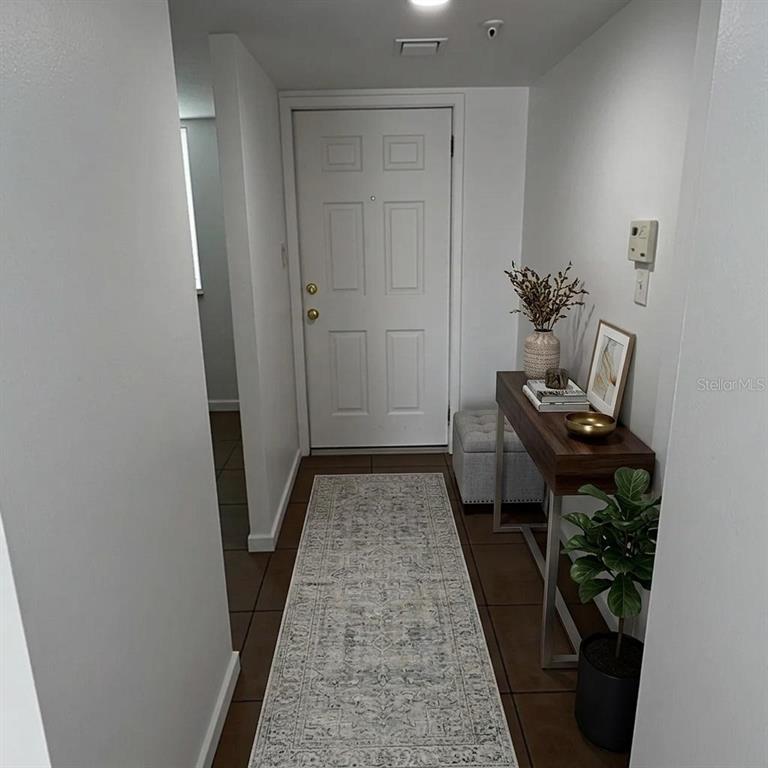 An entryway features a white door, a console table, a runner rug, and tile flooring — 201 W LAUREL STREET UNIT 703, TAMPA, FL
