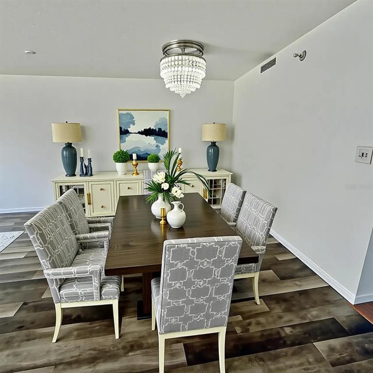 A dining room features a dark wood table, patterned chairs, a crystal chandelier, and a sideboard — 201 W LAUREL STREET UNIT 703, TAMPA, FL