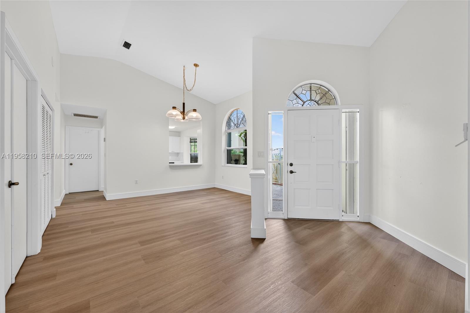 An entryway leads into a living area with vaulted ceilings, wood flooring, and arched windows — 1251 E Wilshire Cir E, Pembroke Pines FL 33027, PEMBROKE PINES, FL