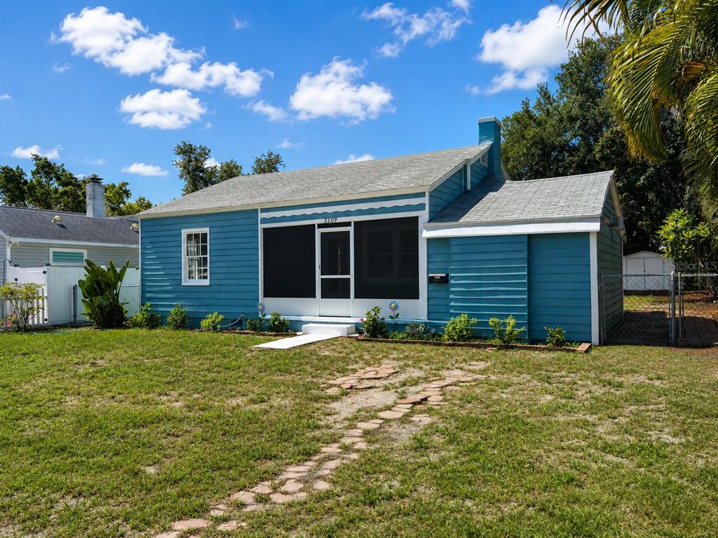A blue single-story house with a screened-in front porch and a stone walkway — 3209 AVENUE A W, BRADENTON, FL