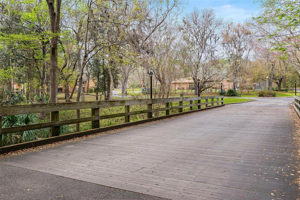 A wooden bridge with railings crosses over a wooded area toward a residential building — 1810 NW 23RD BOULEVARD Bldg 5, 211, GAINESVILLE, FL