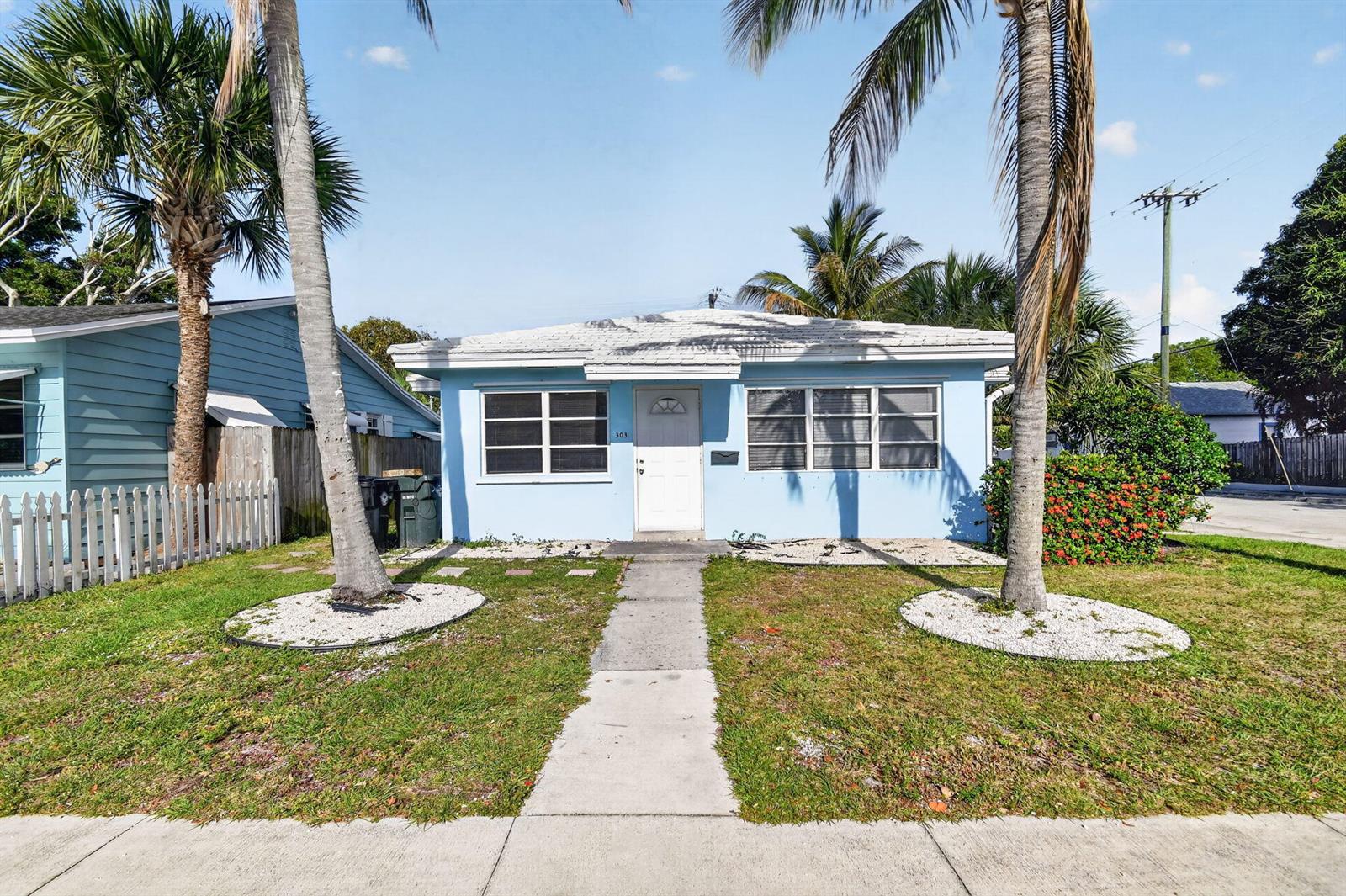 A light blue single-story house features a white front door and two palm trees — 301 S L Street, FL 33460, FL
