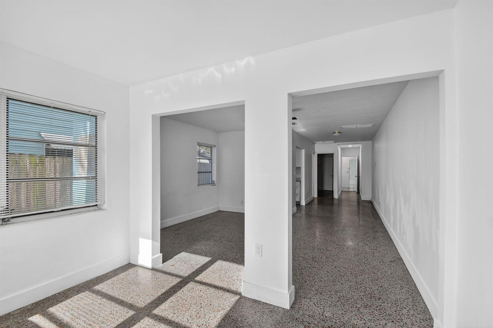 An interior view of a room with terrazzo flooring and white walls leading to hallways — 301 S L Street, FL 33460, FL