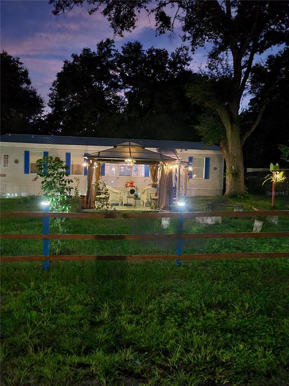 A mobile home with a gazebo in the yard is enclosed by a wooden fence — 12950 SE 104TH COURT, BELLEVIEW, FL