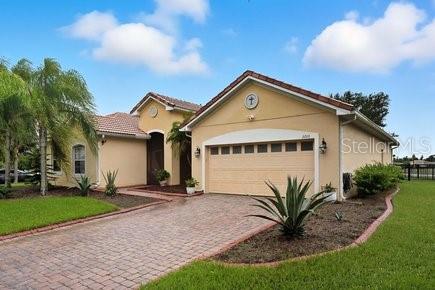 A single-story house with a tan stucco exterior, a two-car garage, and a brick driveway — 3010 WINDING TRAIL, KISSIMMEE, FL