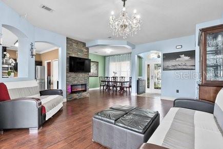 A living room features a stone fireplace, a chandelier, and two sofas on wood flooring — 3010 WINDING TRAIL, KISSIMMEE, FL