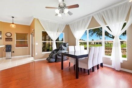 A dining room features hardwood floors, a ceiling fan, and large windows with white curtains — 3010 WINDING TRAIL, KISSIMMEE, FL