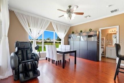 A dining room features a dark wood table, white chairs, and a black massage chair — 3010 WINDING TRAIL, KISSIMMEE, FL