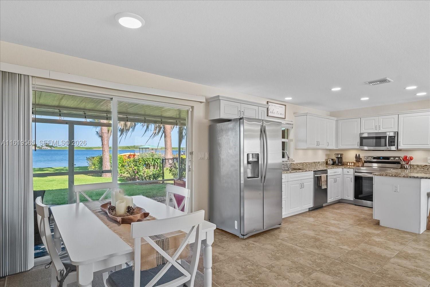 A kitchen and dining area with white cabinets, stainless steel appliances, and a lake view — 924 Lake Dr E, Lake Placid FL 33852, LAKE PLACID, FL