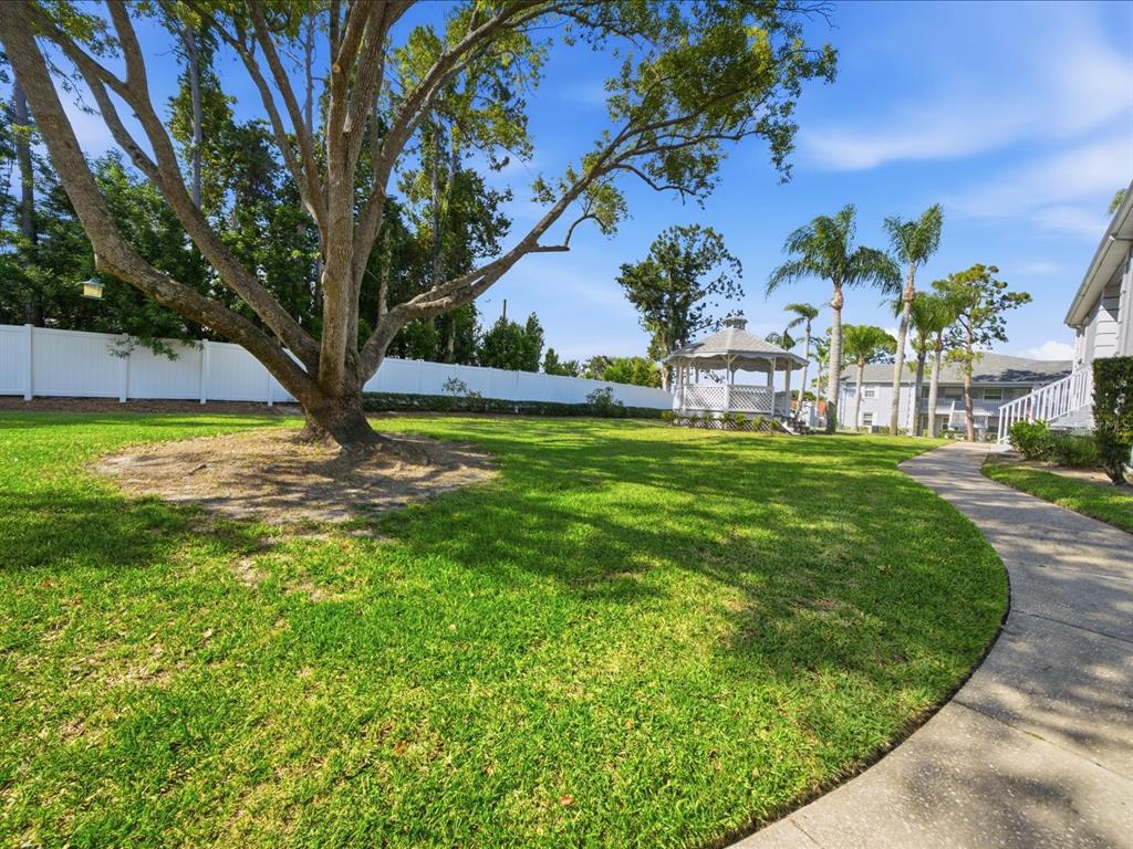 A large tree stands on a grassy lawn near a gazebo and a paved walkway — 12130 SPARTAN WAY UNIT 103, HUDSON, FL