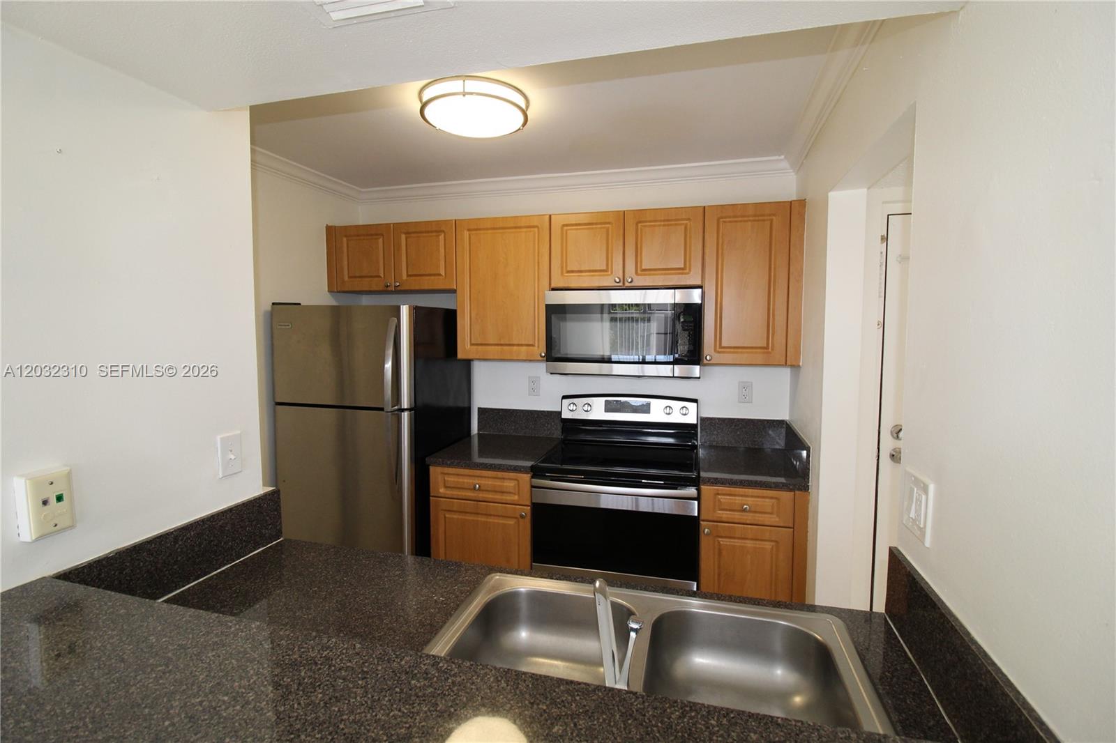 A kitchen features wood cabinets, stainless steel appliances, and dark granite countertops — HIALEAH, FL