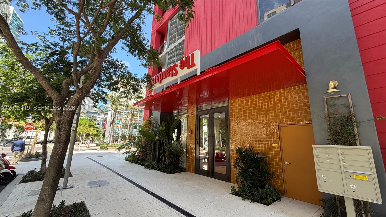 The exterior entrance of a building features a red awning, yellow tiles, and glass doors — 90 NE 32nd St # 1125, Miami FL 33127, MIAMI, FL