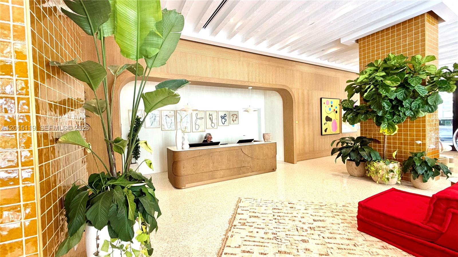 A modern lobby features a reception desk, yellow tiled walls, and several large potted plants — 90 NE 32nd St # 1125, Miami FL 33127, MIAMI, FL