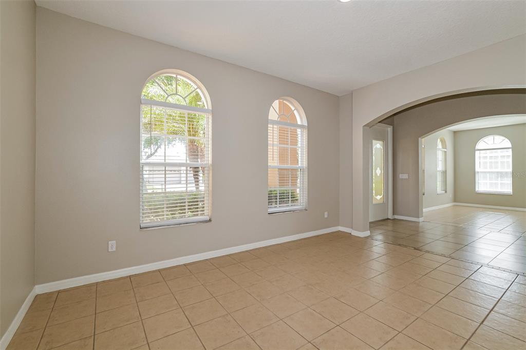 An empty room with beige walls, tile flooring, and two arched windows — 99 JAKE COURT, OCOEE, FL