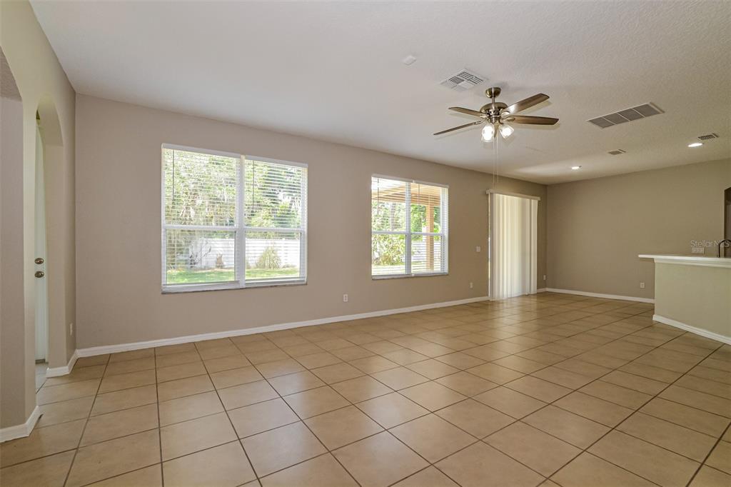 A spacious living room features beige tile flooring, neutral walls, large windows, and a ceiling fan — 99 JAKE COURT, OCOEE, FL