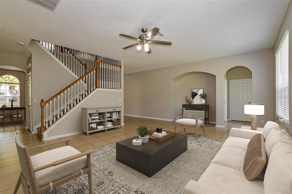 A living room features a staircase, tile flooring, a ceiling fan, and neutral-toned furniture — 99 JAKE COURT, OCOEE, FL