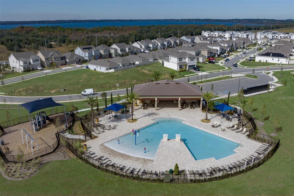 An aerial view shows a community swimming pool, playground, and clubhouse surrounded by suburban homes — 14724 CRESTAVISTA AVENUE, CLERMONT, FL