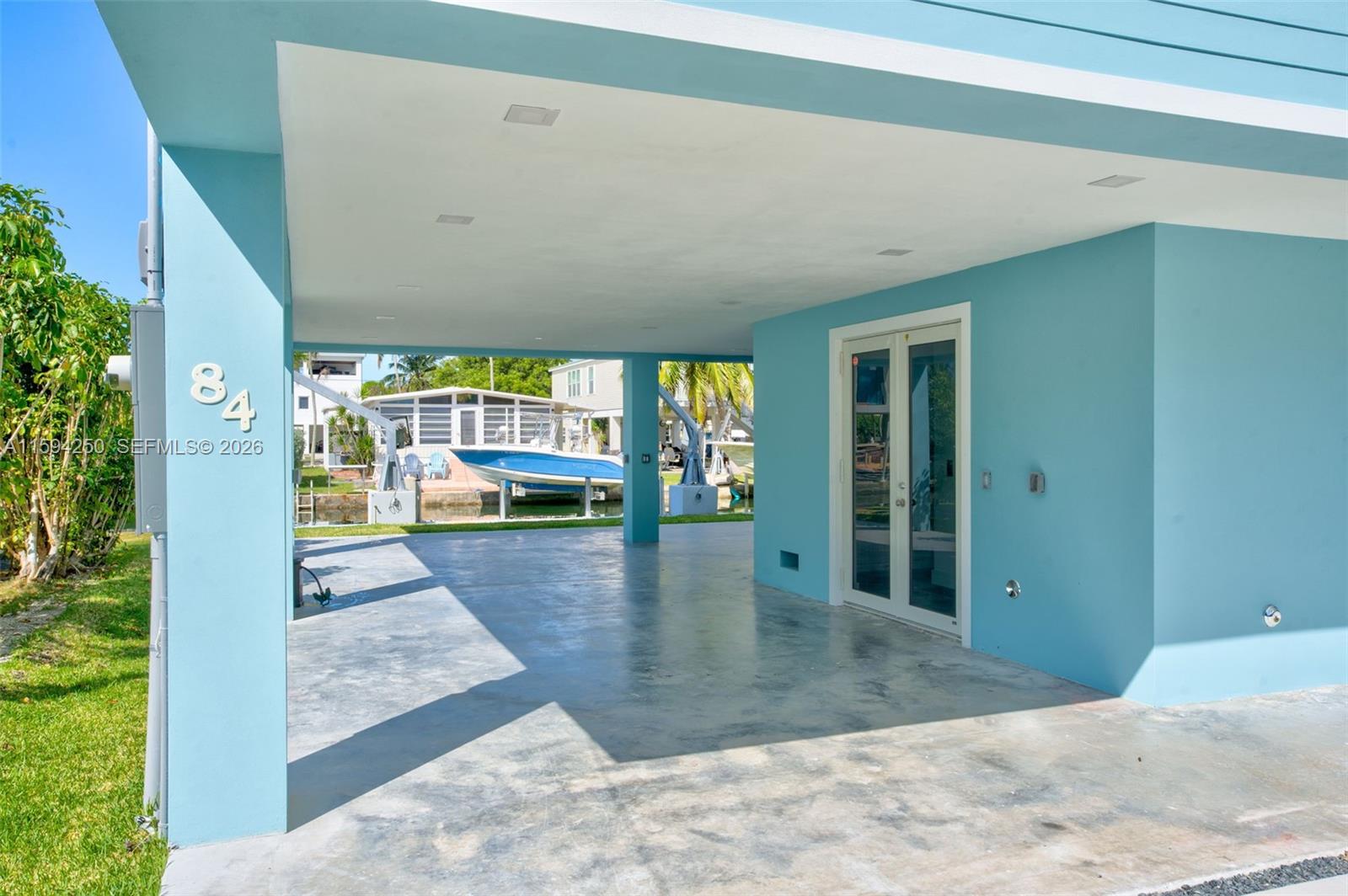 A covered concrete patio area features light blue walls, recessed lighting, and glass double doors — 84 Coral Way, Key Largo FL 33037, KEY LARGO, FL