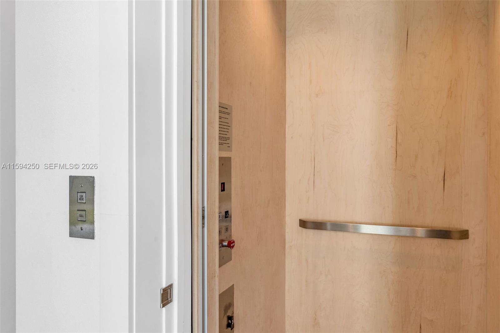 An elevator interior features light wood paneling, a metal handrail, and a control panel — 84 Coral Way, Key Largo FL 33037, KEY LARGO, FL